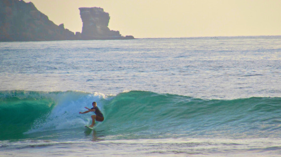 surfer riding a wave in las tunas surf spot ecuador